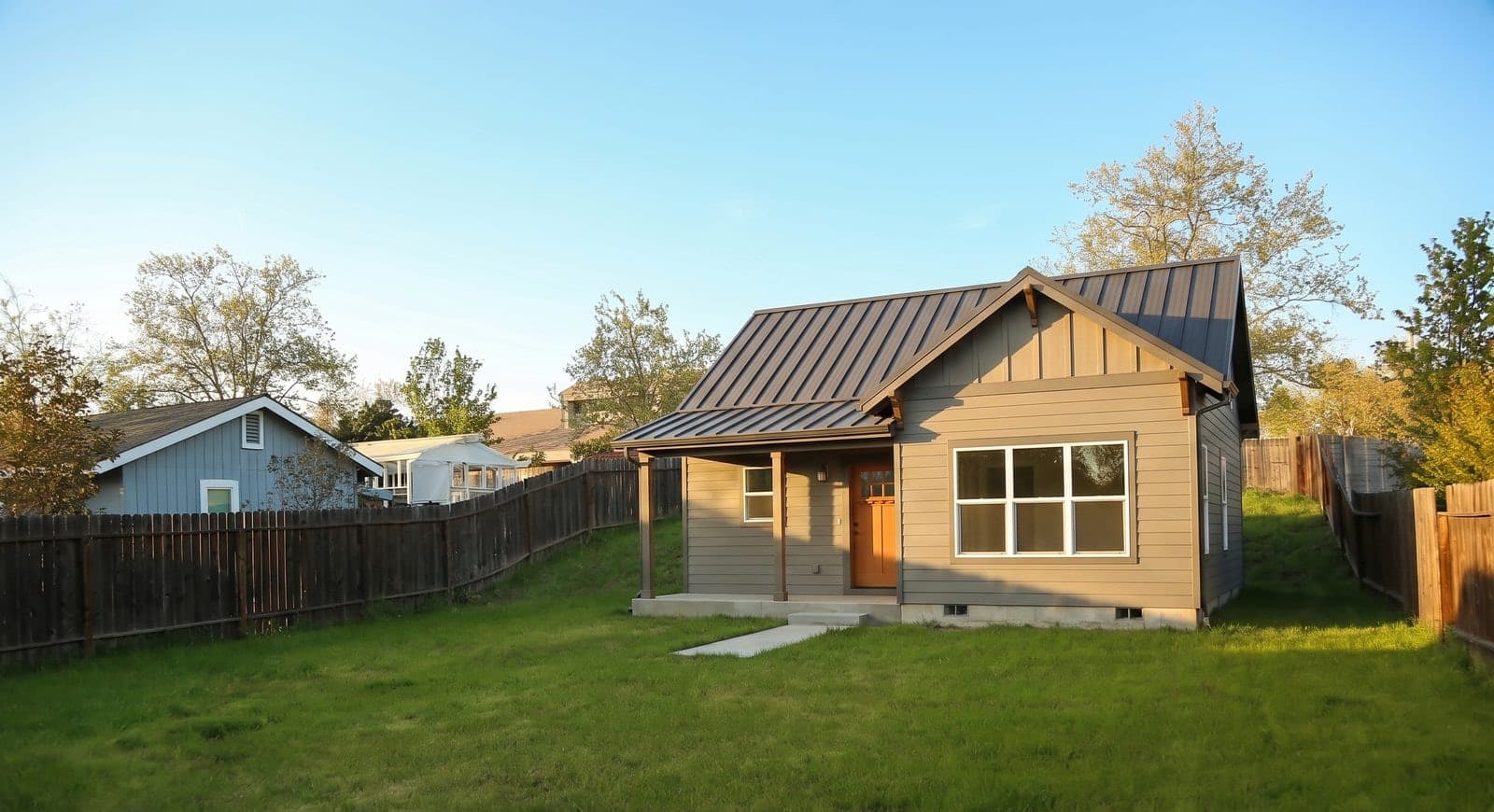 The finished ADU: board-and-batten siding, a standing-seam metal roof, and a covered porch