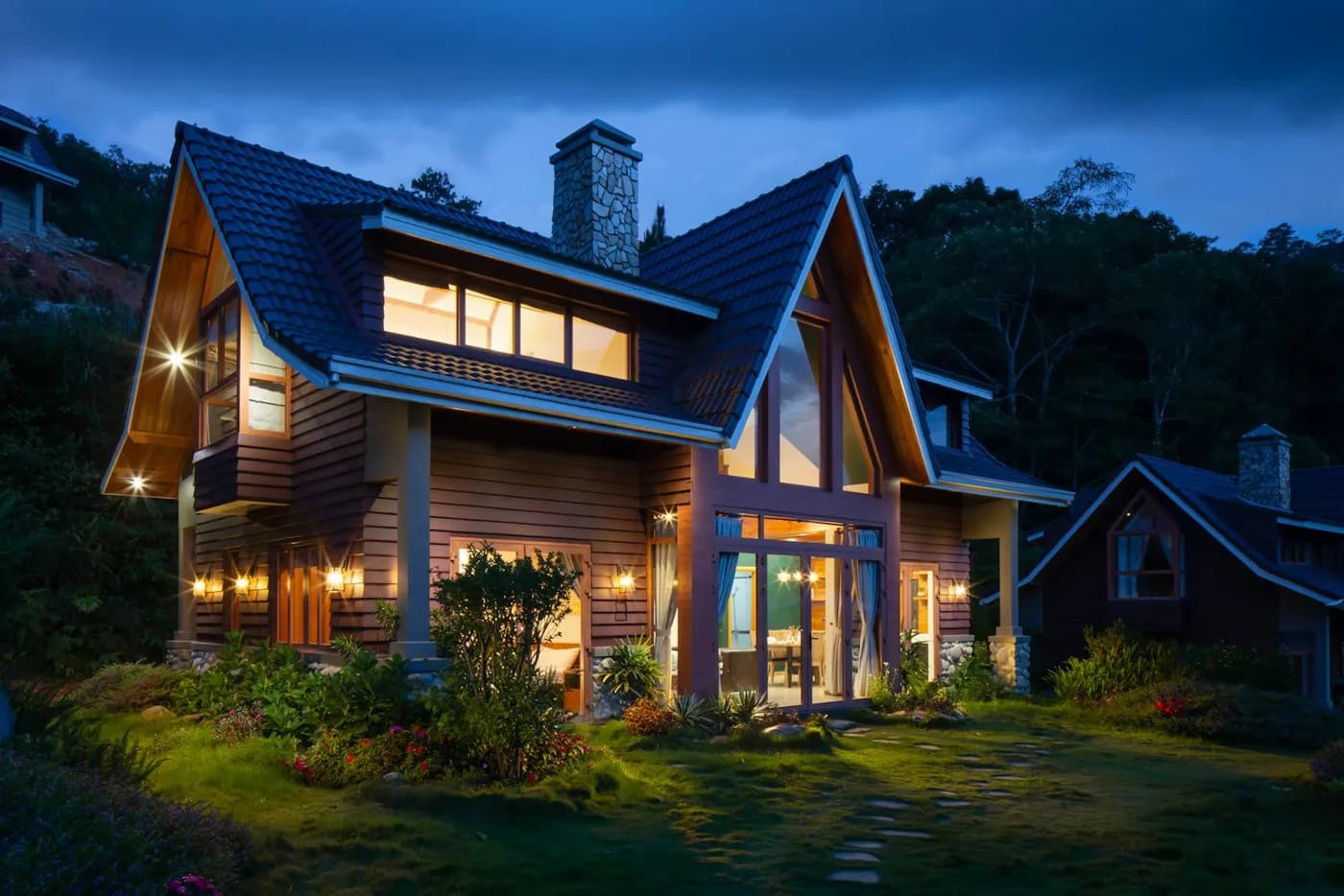 The renovated shingled hillside home glowing at dusk