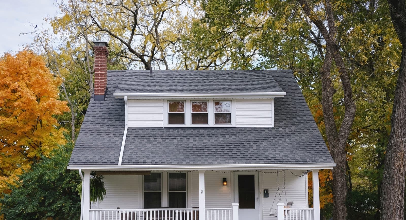 The restored exterior: new grey architectural shingles, crisp white siding, and a repainted porch