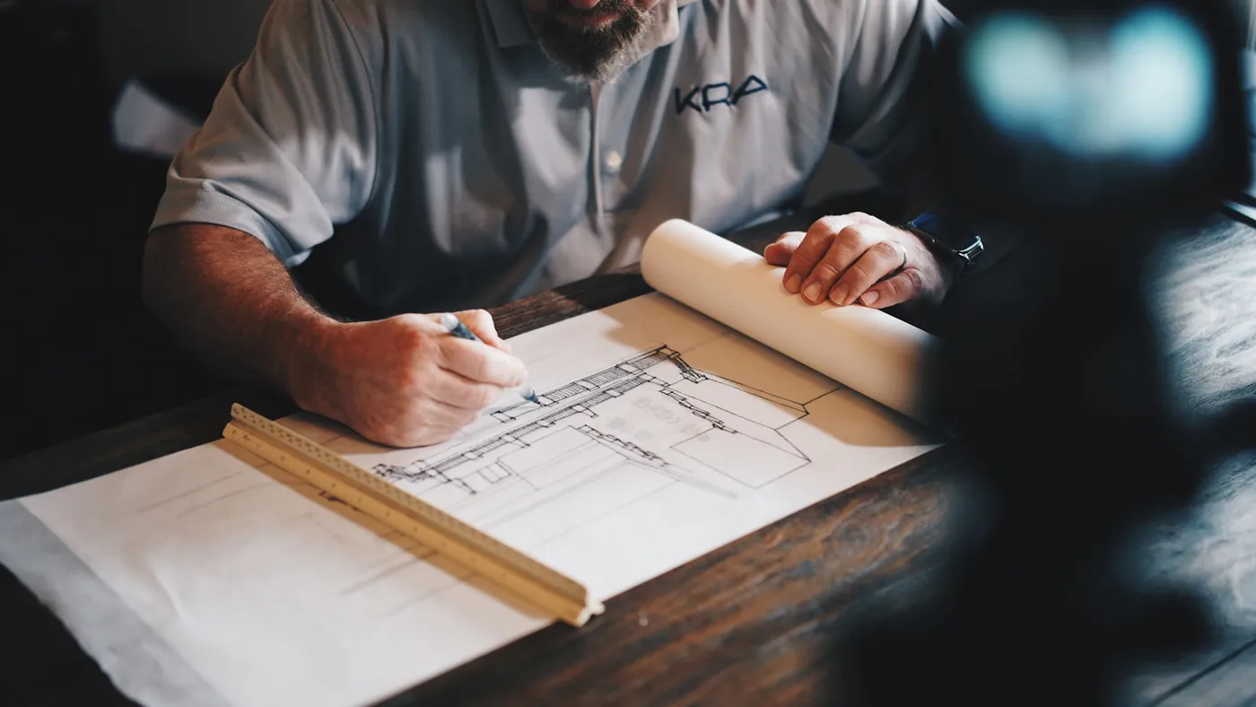 Sam Whitaker marking up framing drawings at the workbench
